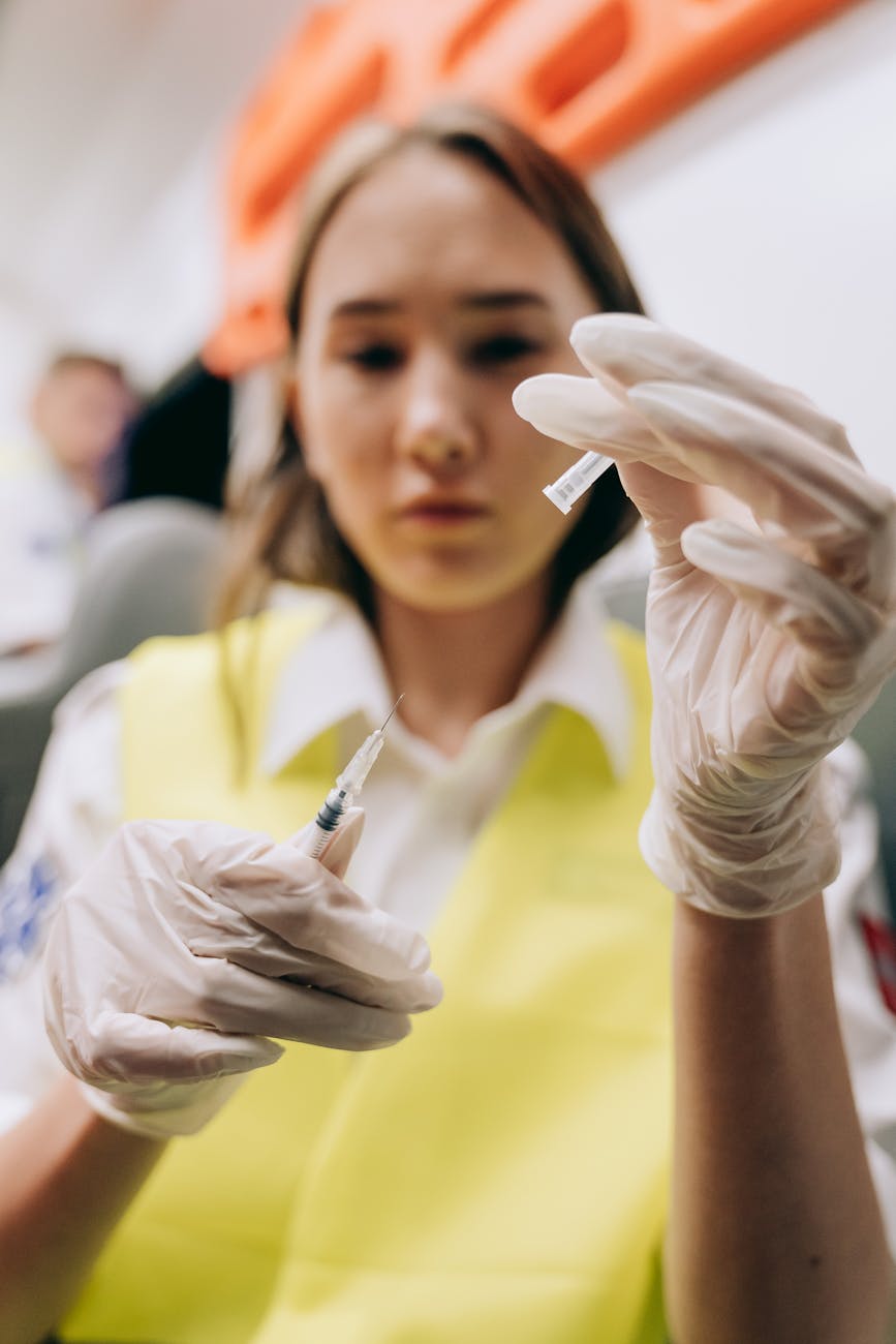woman in white medical gloves holding a syringe